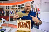 Guy Fieri holding and pointing to a small plaque that says “Flavortown”.