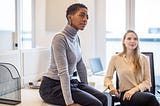 A photo of a black woman in a work meeting with a perplexed expression.