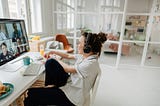 Young woman sitting at a desk and participating in a video conference.