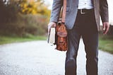 Man with shoulder bag and bible walking down a street