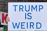 Woman Holding a sign that reads “Trump Is Weird” in bold lettering