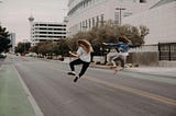 two girls jumping in the air in the middle of city road, they look like they succeeded
