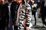 A man wears a black and white zebra print bomber jacket from the brand “Stone Island.”