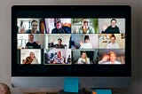 Friends waving to each other during a large video conference call on a computer screen.