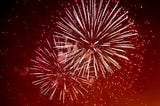 A photo of fireworks against a red night sky.