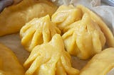 The rice-based dumplings known as ukadiche modak flavored with mango pulp and folded into little purses. These dumplings are bright yellow in colour.