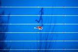 An aerial photo of a person running on a track. Their shadow looks like it’s running.