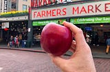 A Cosmic Crisp apple in front of a public market.