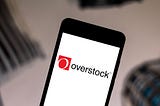 A photo of the Overstock logo on a smartphone.