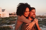 Multiracial couple embracing while watching a sunset.