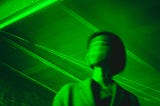 Green fuzzy image of person with blurred out face