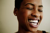 A closeup of a black woman smiling/laughing widely.