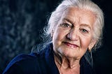 Close up of a beautiful old woman with white hair staring directly into the camera with wisdom in her eyes.