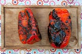 Charred red peppers on a wooden board.