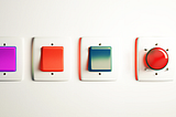 A row of rendered light switches of various colors with a big red launch button at the end.