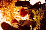 A man and a woman wearing pumpkin masks on Halloween, both have one leg raised kicking something