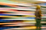 A person walking toward the right side of the pic against a colorful, motion-blurred background.