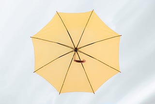 Photo of a yellow umbrella open in a cloudy sky.