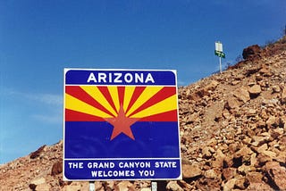 A “Welcome to Arizona sign” at the state border. This article is about whether tax changes cause the wealthy to flee. Funny?