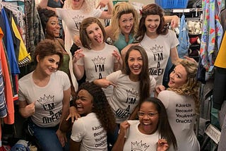 A group of young girls, wearing shirts saying “I’m a Queen” pose, smile, and laugh.