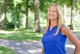 Kristin Ihle Helledy outside in front of a forest wearing a blue shirt