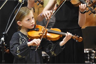 talented young woman playing violin in a concert hall
