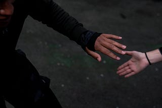 A color photograph by Brendan Davis of the hands of two people reaching for one another during an exercise routine.