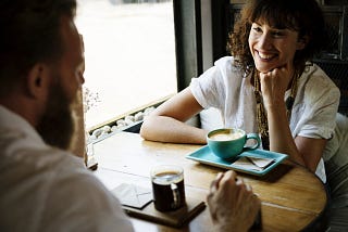 Man (left) and woman (right) in a conversation in a cafe