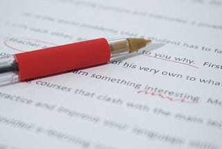 A red pen used to edit an essay lying on a piece of paper it was used to mark