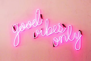 A pink neon sign that reads “good vibes only” on a pink background.