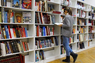 Young woman standing in front of shelves of books.
