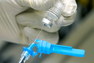 A registered nurse prepares a syringe with the first round of the Pfizer COVID vaccination