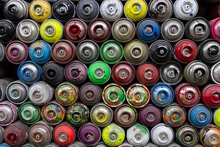 A pile of spray paint cans of many different colors