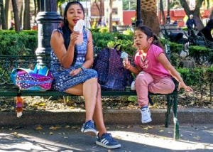A mother and her daughter eating a yummy ice cream in a public park in Mexico City