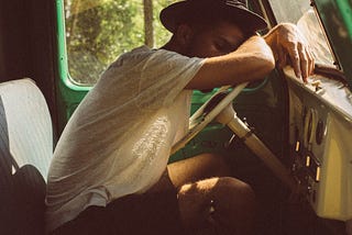 A man sleeping at the wheels of a car