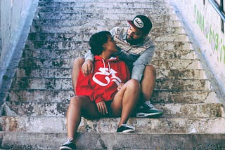 A photo of two friends sitting on stairs and embracing.