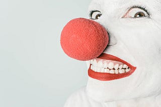 White clown face with red lips and a big red nose.