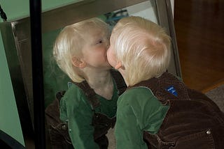 young child kissing self in mirror