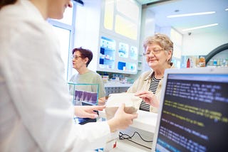 Pharmacist handing medication to customer