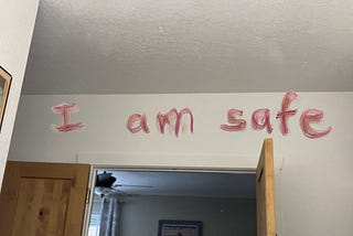 The words “I am safe” written in lipstick on a mirror