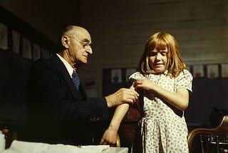 Image of an old doctor giving a girl a jab