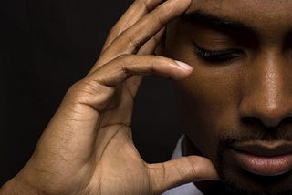 Man with hand on his head, eyes closed and thinking