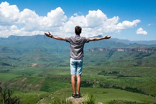 Man Standing in With Open Arms in Green Scenery