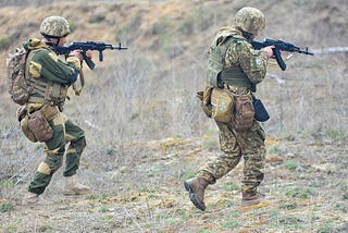 UAF infantry assault a position with AKMs and forest combat fatigues.