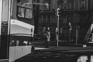 black and white image of a white woman waiting at a train crossing