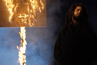 Jermaine Cole standing in front of a burning basketball hoop