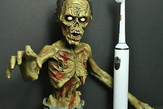A gaunt toy zombie with outstretched hand and an electric “smart” toothbrush. Image generated by Google Bard AI.