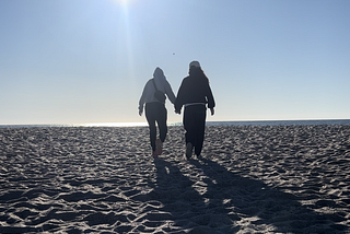 best friends holding hands and walking on the beach