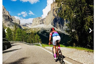 A female cyclist in colourful kit rides a road bike into a gorge in the French Pyrenees