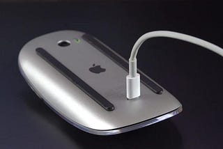 A magic mouse that is plugged in and charging.